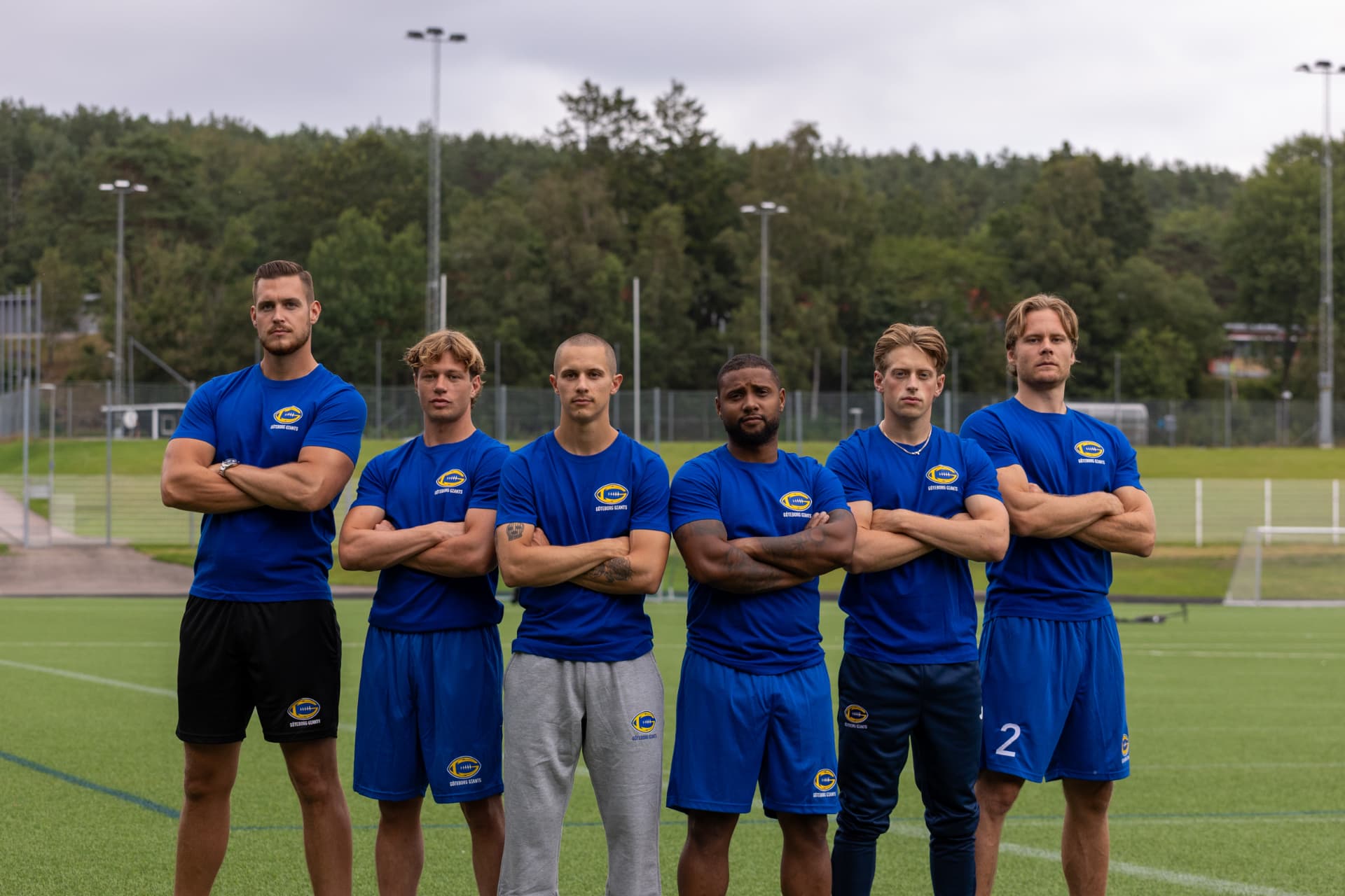 Sex spelare från Göteborg Giants i blå matchtröjor på en konstgräsplan